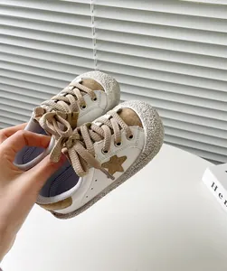 Nahaufnahme atmungsaktiver weißer Kleinkind-Sneaker mit braunem Sterndesign und Sohle