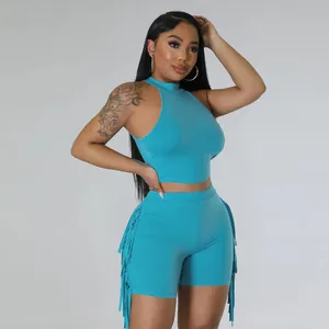 Full view of model wearing vibrant blue sleeveless crop top and tassel fringe shorts set.