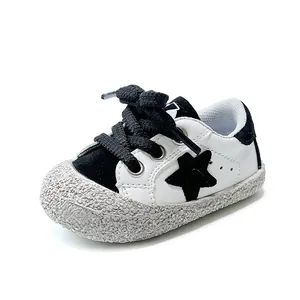 Weiche Lauflernschuhe für Kleinkinder mit schwarzem Sterndesign auf weißem Leder-Obermaterial.