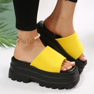 Close-up of vibrant yellow square-toe platform wedge slides on model feet with anklet
