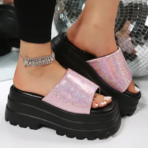 Close-up of women's pink glitter platform slides with thick black soles and shimmering straps