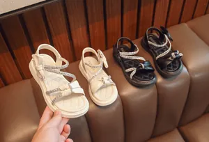 Elegant girls' rhinestone bow sandals in cream and black with comfortable soft soles.