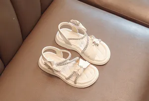 Detailed view of fashionable cream girls sandals with rhinestone bow decorations