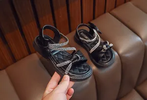 Close-up of black girls' sandals with sparkling rhinestones and elegant bow detail