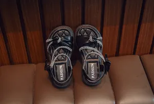 Detailed view of fashionable girl's black sandals featuring sparkling rhinestone straps.