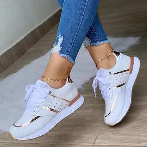 Primo piano di sneaker platform bianche con dettagli in oro rosa e lacci.