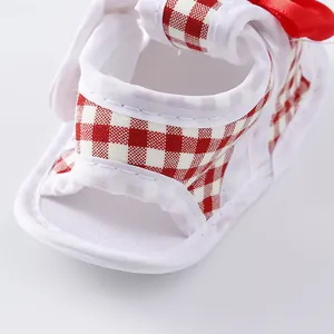 Detailed view of red and white checkered baby sandal with soft sole and decorative bow