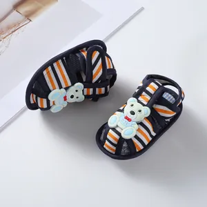 Close-up detail of striped baby sandals featuring cute bear decoration and soft walking sole