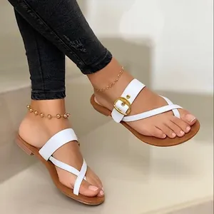 Detailed close-up of women's white flat sandals featuring a toe loop and golden buckle
