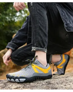 Detail view of grey and yellow breathable outdoor hiking shoes on rocky ground.