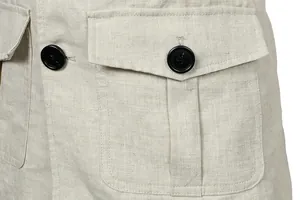 Close-up detail of a men's linen cargo jacket featuring flap pockets and black contrast buttons