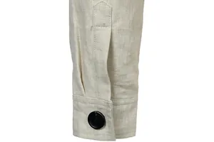 Detailed view of a men's linen jacket cuff featuring a black button and fine stitching