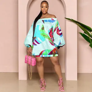 Vestido corto estampado con hombros descubiertos, mangas murciélago y bolso rosa.