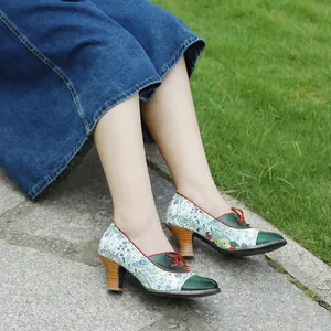 Close-up of vintage floral print high heel pumps with green leather toe cap and red laces.