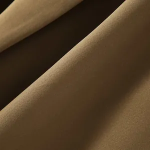 Κοντινό πλάνο καφέ υφάσματος που δείχνει τη λεπτή ύφανση και την πτώση ενός γιλέκου.