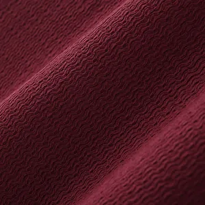 Vue rapprochée du tissu bordeaux présentant une texture tricotée ondulée unique.