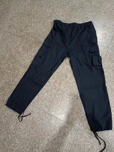 Détail d'un pantalon cargo noir pour homme avec chevilles à cordon et poches latérales.