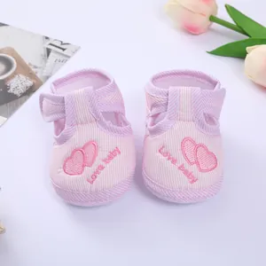 Close-up of pink striped baby shoes with embroidered heart pattern and Love baby text