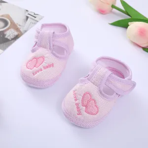 Macro detail of pink striped baby walking shoes featuring embroidered hearts and Love baby text