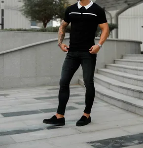 Detail view of a men's slim fit black polo shirt featuring a white collar and chest stripe