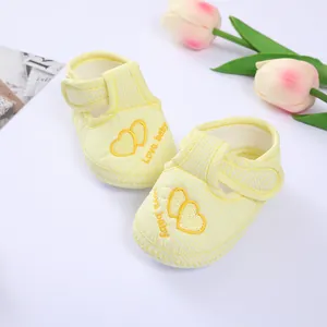 Close-up of soft yellow striped baby walking shoes with embroidered heart patterns and text