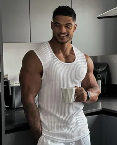 Muscular man wearing a white ribbed knitted gym vest in a modern kitchen setting