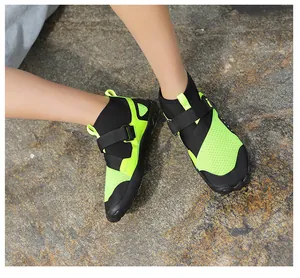 Detailed view of neon green high-top breathable water shoes on outdoor rocky ground