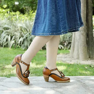 Side view of retro brown leather Mary Jane pumps with flower detail on model's feet