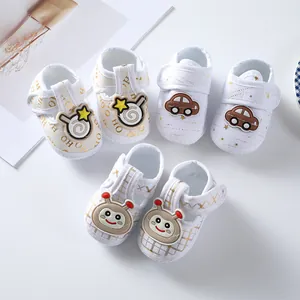 Detailed view of soft-sole newborn fabric shoes with cute cartoon motifs and gold prints