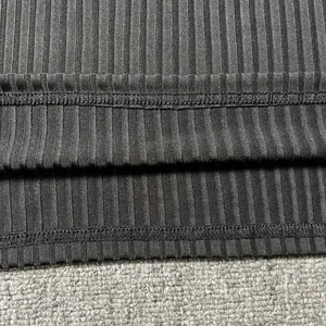 Close-up macro view of the neat stitching and vertical ribbed knit texture on the black fabric hem