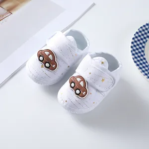 Close-up of white soft-soled baby shoes with gold star patterns and cartoon car decor