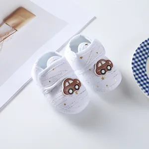 Detail of soft-sole newborn baby shoes featuring a car patch and gold star patterns.