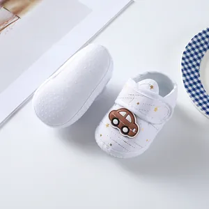 Detailed view of white newborn baby shoes featuring brown car patch and soft anti-slip cloth sole