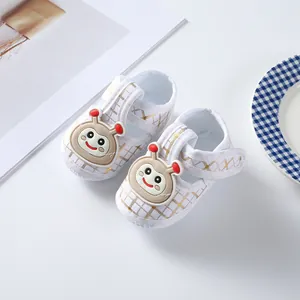 Detailed view of baby soft sole shoes with gold plaid and cute bee character decoration.