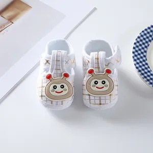 Detail of white baby soft sole shoes with golden plaid and cute cartoon character