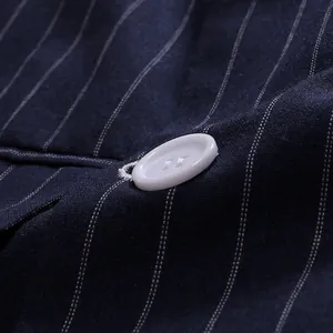 Close-up detail of white button and navy pinstripe fabric on a men's suit jacket.