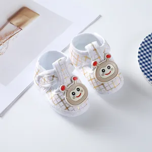 Detail view of white soft-sole baby shoes with gold grid pattern and cartoon character