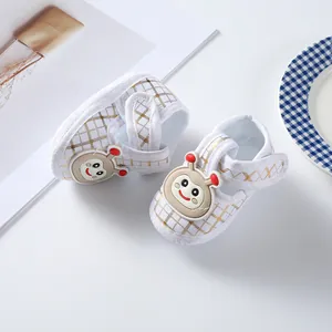 Detail of baby soft-sole shoes with gold grid pattern and cute cartoon snail.