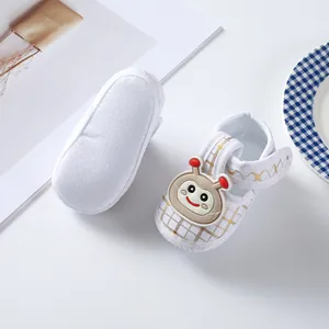 Detailed view of white baby shoes with gold plaid pattern and soft anti-slip sole