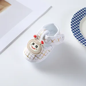 Close-up of white baby cloth shoe with gold grid and cute cartoon snail