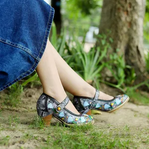 Seitenansicht von Retro-Mary-Jane-Pumps mit Stickerei und dicken Holzabsätzen auf Gras.