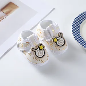 Detailed view of cream baby shoes with gold 'HO HO' pattern and star patch decoration