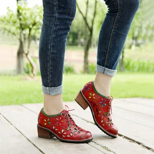 Detail shot of vintage red leather lace-up shoes with colorful floral hollow out design.