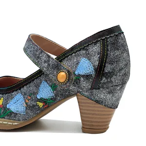 Nahaufnahme der retro Blumenstickerei auf metallisch silbernen Mary Jane Blockabsatz Schuhen.