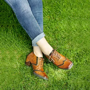Vista detallada de zapatos vintage de cuero marrón con cordones y tacón ancho en césped