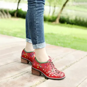 Detail view of vintage red leather shoes featuring multicolored flower cutouts and lace-up design