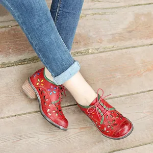 Close-up of red genuine leather shoes with hollow flower patterns and retro laces.