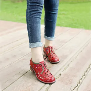 Detailed shot of retro red leather cutout lace-up shoes on a wooden outdoor deck.