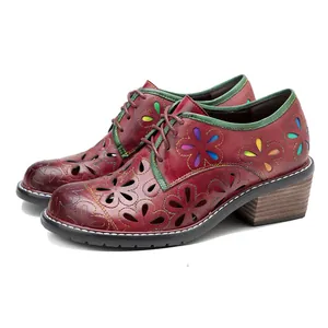 Close-up side view of vintage red leather shoes with colorful floral hollow-out details.