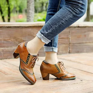 Primer plano de zapatos vintage de cuero marrón con cordones, remaches y tacón de bloque.